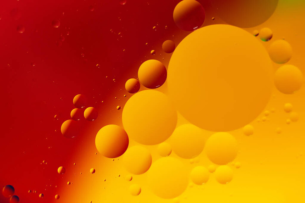 Macro fotografie van de olie druppels op het wateroppervlak.Levendige rode en oranje gradiënt Cosmische cirkels ziet eruit als molecuul structuur.Achtergrond met kopieerruimte, goed als sjabloon. - Foto, afbeelding