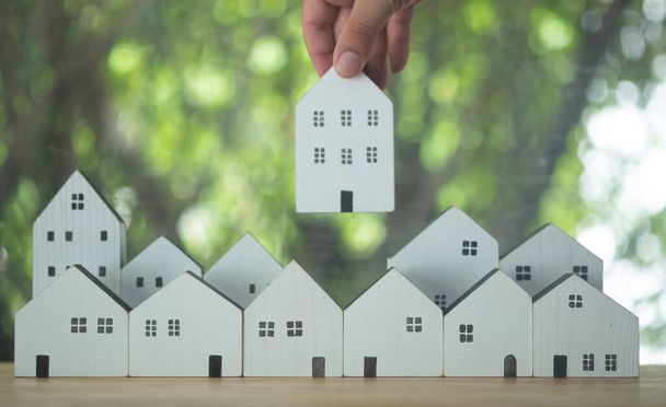 Homme choisir à la main pour sélectionner un modèle de maison sur le bois sur la table. Prêt pour l'immobilier ou économiser de l'argent pour acheter une nouvelle maison à la famille dans le futur concept. Choisissez ce qui est le meilleur. - Photo, image