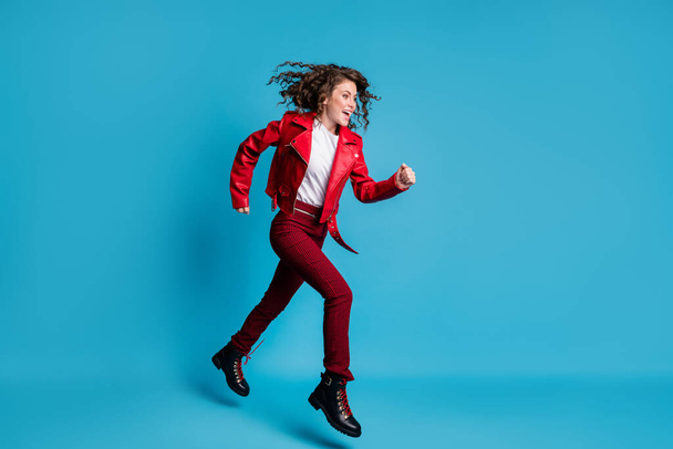 Photo of sweet charming young lady wear red clothes jumping running looking empty space isolated blue color background - Foto, afbeelding