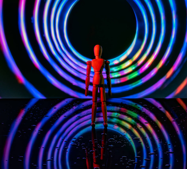 Un hombre articulado se para frente a un embudo multicolor giratorio - Foto, Imagen