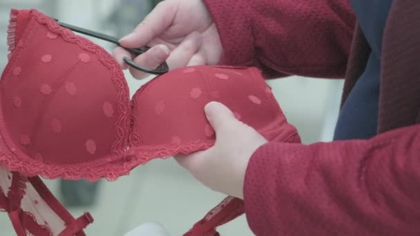 妊婦は衣料品店で大きな赤いブラジャーを選択します。手を閉じるショット - 映像、動画