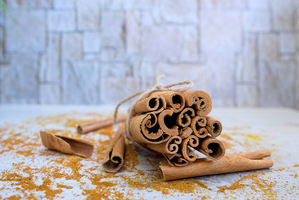 background of cinnamon sticks in stacks on a wooden table in white color - Фото, зображення