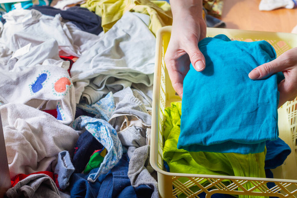 A woman puts a rolled-up blue T-shirt in a clothing storage box - Photo, image