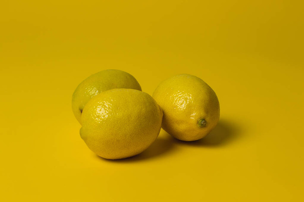Three lemons isolated on yellow background - Photo, Image