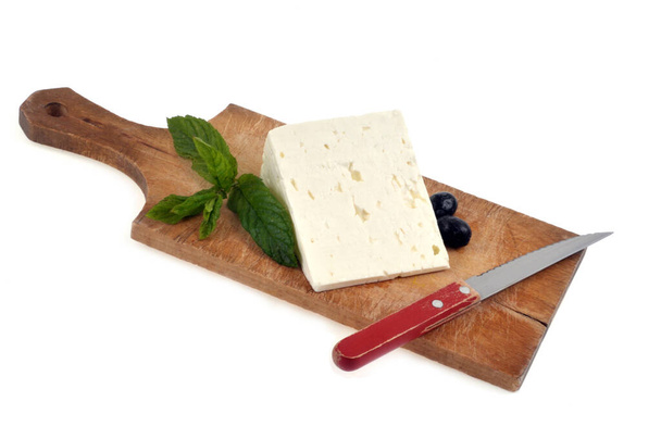 Bıçak, siyah zeytin ve beyaz arka planda yakın plan nane yapraklı kesilmiş peynir dilimi. - Fotoğraf, Görsel