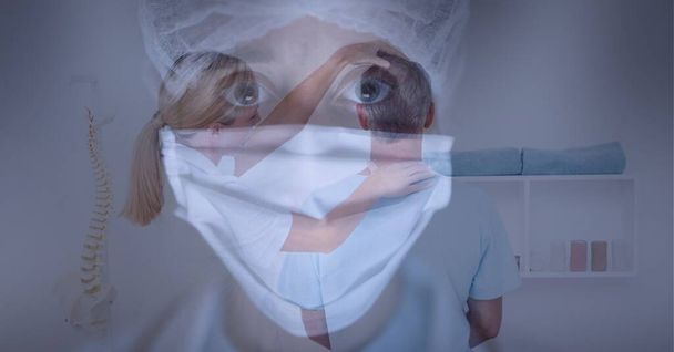 Caucasian female doctor wearing facemask against female doctor examining neck of male patient. medical healthcare during coronavirus covid 19 pandemic concept - Photo, Image