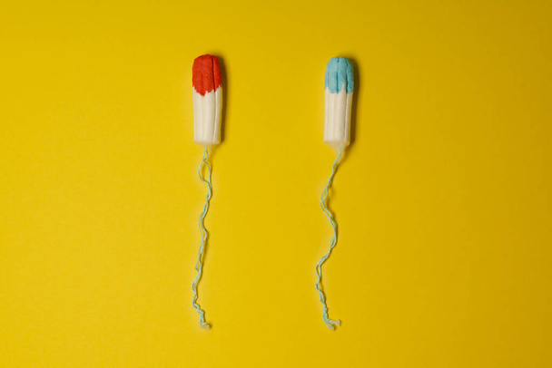 Tampons soaked in blue and red fluid as concept of uncomfortable female truth shown unreal in advertisements for mentruation products - Foto, Imagen