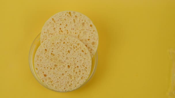 Limpadores cosméticos spa esfregadores faciais em respingo de água no fundo amarelo - Filmagem, Vídeo