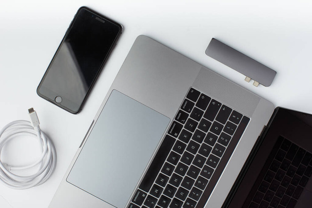 白の背景にある、黒のスマートフォン、 USB Type-Cケーブル、 USBハブ、ラップトップのトップビュー写真. - 写真・画像