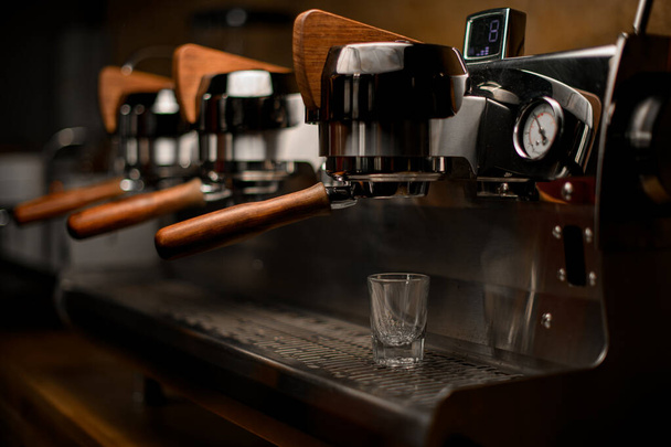 empty glass on steel surface of professional coffee machine in coffee shop - Foto, afbeelding