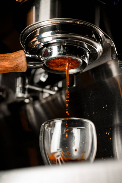 Coffee machine pouring coffee drink in double wall glass from bottomless naked portafilter. - Foto, Imagem