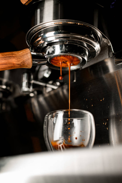 Coffee machine pouring coffee in double wall glass from bottomless naked portafilter. - Foto, imagen