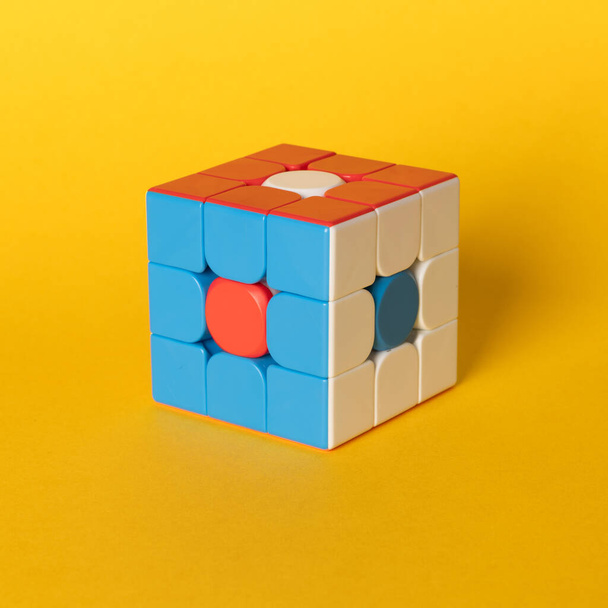 Colourful Rubik cube placed on a coloured background. There is three sides of the cube visible. - Φωτογραφία, εικόνα