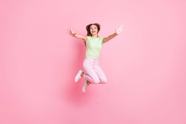 Full length photo of attractive carefree lady hands raise to you jumping have fun isolated on pink color background - Fotoğraf, Görsel
