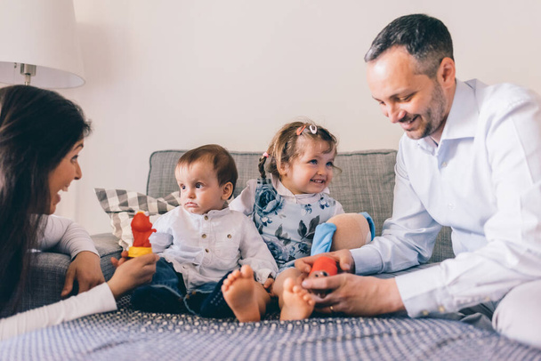 Famiglia felice con due bambini al coperto a casa a giocare insieme - Foto, immagini