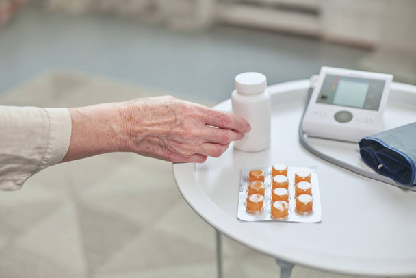Magas vérnyomás, gyógyszeres kezelés. Gyógyszerek és vérnyomásmérő a fehér asztalon. Gyógyászat és egészséges életmód - Fotó, kép