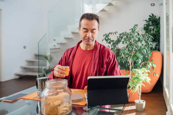 Single adult man relaxing indoor at home using tablet drinking coffee  - Photo, Image