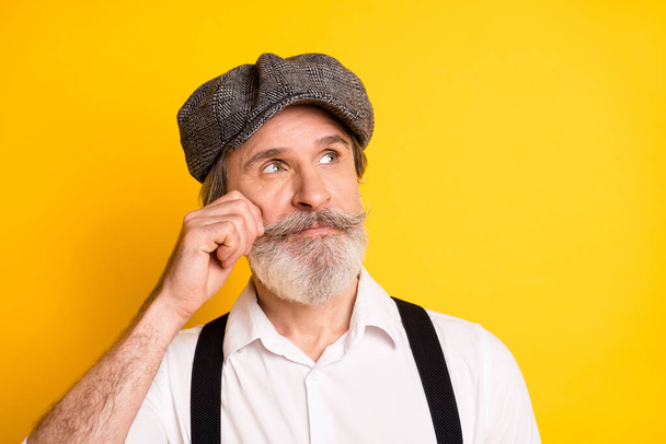 Photo of aged man hand touch cheek dream dreamy think look empty space isolated over yellow color background - Zdjęcie, obraz