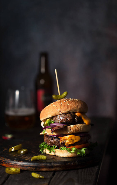 Domowy burger z dwoma kotletami i roztopionym serem z piwem i frytkami - Zdjęcie, obraz