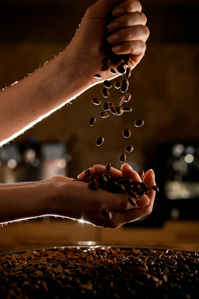 uitzicht op vrouwelijke handen met koffiebonen die gieten van de ene naar de andere hand - Foto, afbeelding