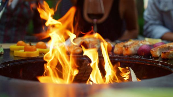 Пламя крупным пламенем горит в барбекю на заднем дворе. Овощи на открытом воздухе - Фото, изображение
