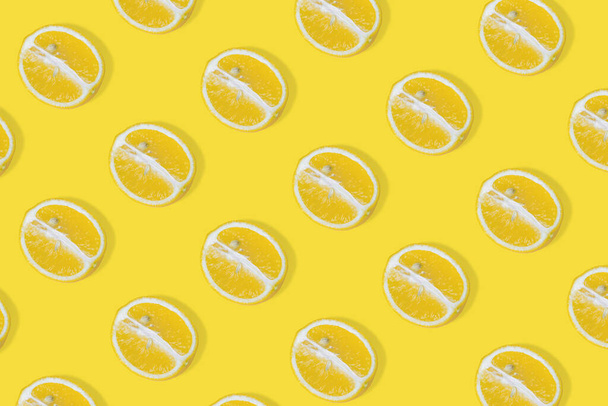 Trendiges Sommermuster mit gelben Zitronenscheiben auf leuchtendem gelben Hintergrund. Minimales Sommerfutterkonzept. Flache Nahrungsmittelkonsistenz - Foto, Bild