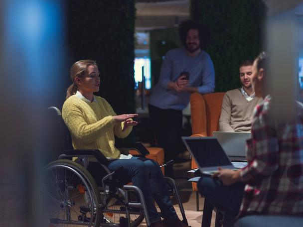 Disabled businesswoman in a wheelchair having a meeting with the diverse business people team at modern startup open space office  - Φωτογραφία, εικόνα