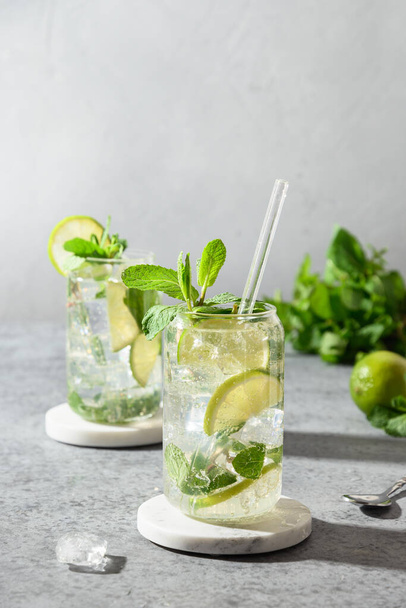 Two mojito with lime, mint, and ice cube on gray background. Close up. - Photo, image