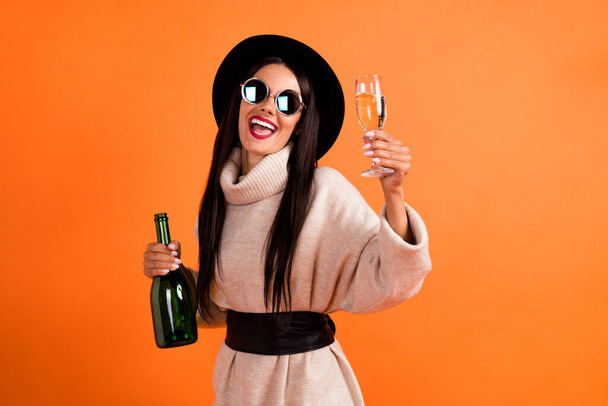 Photo of young beautiful lovely charming smiling girl in sunglasses drinking champagne isolated on orange color background - Fotografie, Obrázek
