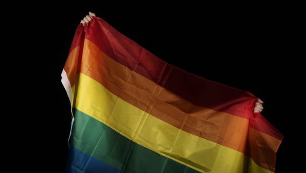Bandiera dell'orgoglio LGBTQ. Lesbica gay bi sessuale transgender queer. Orgoglio omosessuale Bandiera arcobaleno in mano gay. sfondo nero. Rappresentare simbolo di libertà, pace, uguaglianza e amore. Concetto LGBTQ.  - Foto, immagini