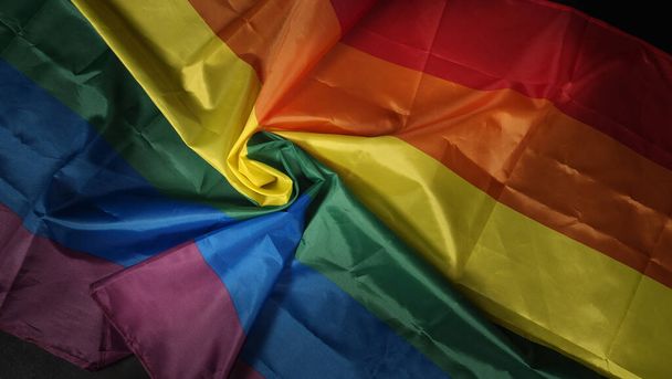 LGBTQ gurur bayrağı. Lezbiyen Gay Biseksüel Cinsiyet Değiştiren Gay. Eşcinsel gururlu gökkuşağı bayrağı eşcinsellerin elinde. Siyah arka plan. Özgürlüğün, barışın, eşitliğin ve aşkın sembolü. LGBTQ kavramı.  - Fotoğraf, Görsel