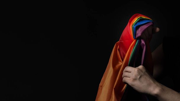 Bandeira de orgulho LGBTQ. lésbica gay bi sexual transexual queer. Orgulho homossexual Bandeira do arco-íris na mão gay. fundo preto. Representa símbolo de liberdade, paz, igualdade e amor. Conceito LGBTQ.  - Foto, Imagem
