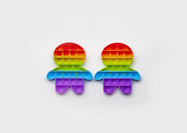 Dvě neposedné postavy s barevnou duhovou vlajkou lgbtq nad bílým pozadím, koncepce homosexuální hrdosti - Fotografie, Obrázek