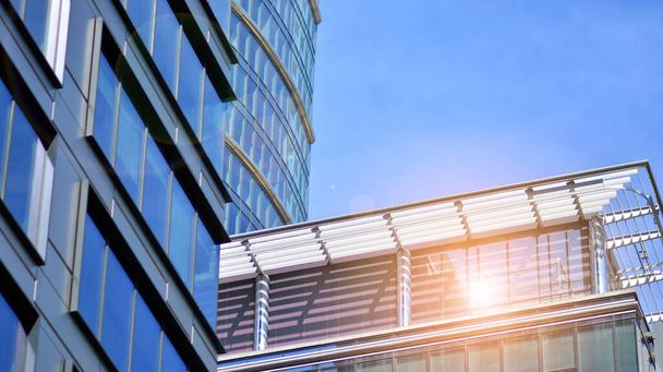 Moderne Architektur mit Sonnenstrahlen. Glas- und Stahlfassade an einem strahlend sonnigen Tag mit Sonnenstrahlen am blauen Himmel. Wirtschaft, Finanzen, Geschäftstätigkeitskonzept. - Foto, Bild