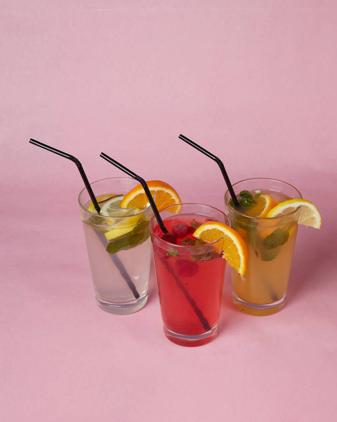 sobre la mesa, refrescos, varios cócteles, un vaso con una paja y una rodaja de limón, un fondo borroso - Foto, Imagen