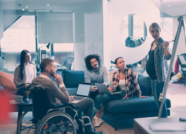 Pregnant Businesswoman Leads Creative Meeting Of Diverse Business Team In Modern Coworking Open Space Office, Disabled coworker in wheelchair attending training  - Foto, imagen
