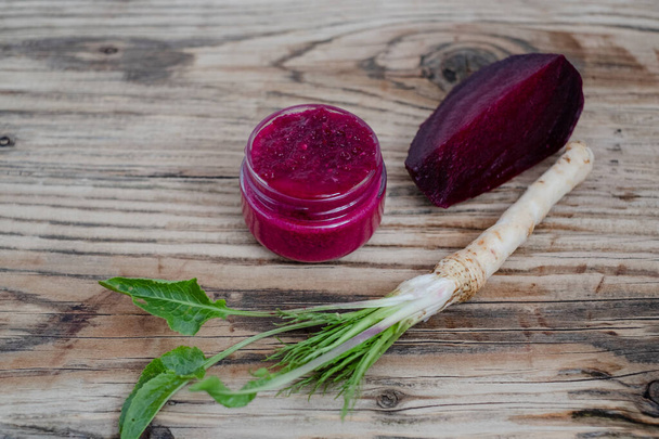 A jar of homemade beet-horseradish hummus. with a spoon in the middle. Organic food isolated on a white background. High quality photo - Photo, Image