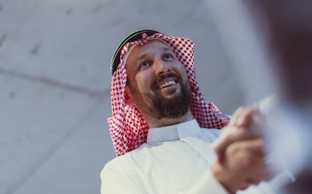 Business meeting with an Arab man and his partner shaking each others hands in greetings and introduction, discussing and planning. High quality photo. Follow focus - Photo, image