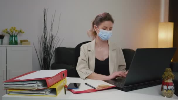 Sick business woman sneezing while working in home office with mask. Pandemic period. Quarantine work mood. Sick Caucasian woman must work from home. Urgent projects. - Footage, Video