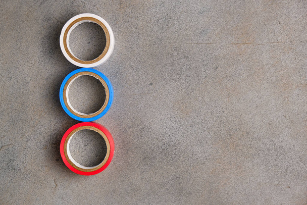 Multicolored electrical tape on an abstract gray background. White, blue, and red duct tape. Top view. Space for lettering and design - Foto, afbeelding