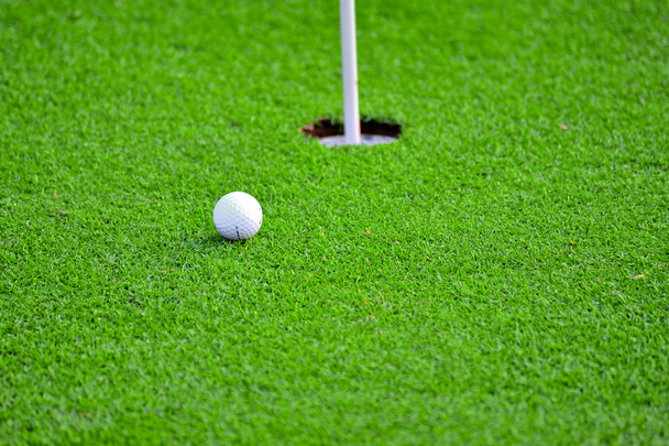 Palla da golf e buca da golf sull'erba verde
  - Foto, immagini