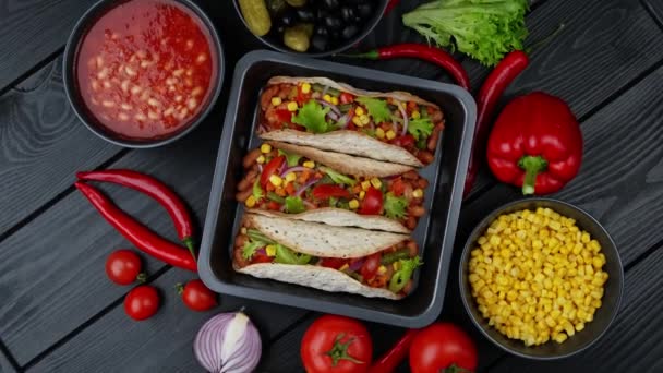 Tradycyjne meksykańskie jedzenie. Smaczne tacos z warzywami. Kolorowe składniki na czarnym tle - Materiał filmowy, wideo