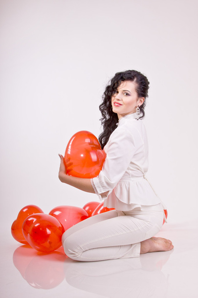 Nainen, jolla on punainen sydän ilmapallo valkoisella taustalla
 - Valokuva, kuva