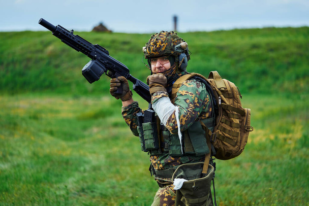 Voják ve vojenské uniformě s obvázanou rukou drží v ruce zbraň. - Fotografie, Obrázek