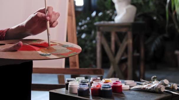 Una joven artista mezclando colores en la paleta del taller de arte - Metraje, vídeo