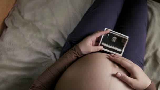 verwacht zwangere vrouw met een grote buik kijken naar echografie scan thuis - Video