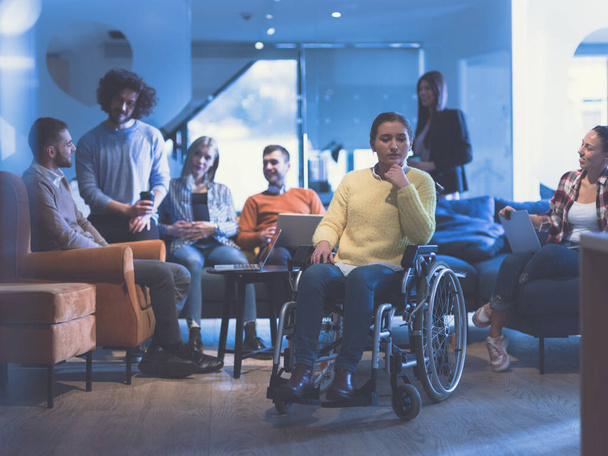 Portrait of disabled businesswoman in a wheelchair in front of her diverse business team at office - Photo, image
