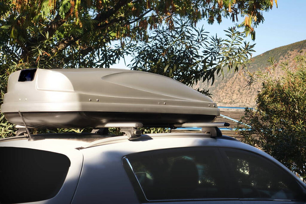 Κουτί φορτηγού αυτοκινήτου στην οροφή. 4WD αυτοκίνητο με αποσκευών στην οροφή στερέωση στο σύστημα Rack. Closeup άποψη του αυτοκινήτου Roof Box στην οροφή. Ταξίδι και Ταξίδι Auto Τουρισμός Τοπίο με βουνό και θάλασσα παραλία. - Φωτογραφία, εικόνα