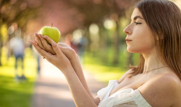 Девушка в парке с яблоком в руке. Портрет - Фото, изображение