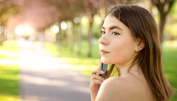 Chica atractiva hablando por teléfono en el parque - Foto, imagen